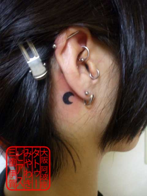 右耳の後ろ側に黒色での小さい三日月のタトゥー