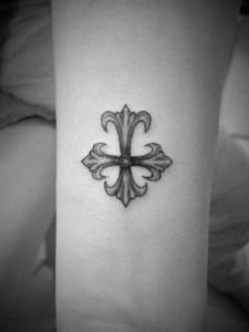 腕にボカシのグラデーションで、小さな十字架のタトゥー。