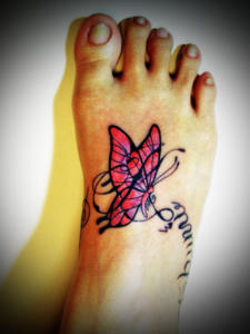 足の甲にピンク系のグラデーションの蝶と、英文字